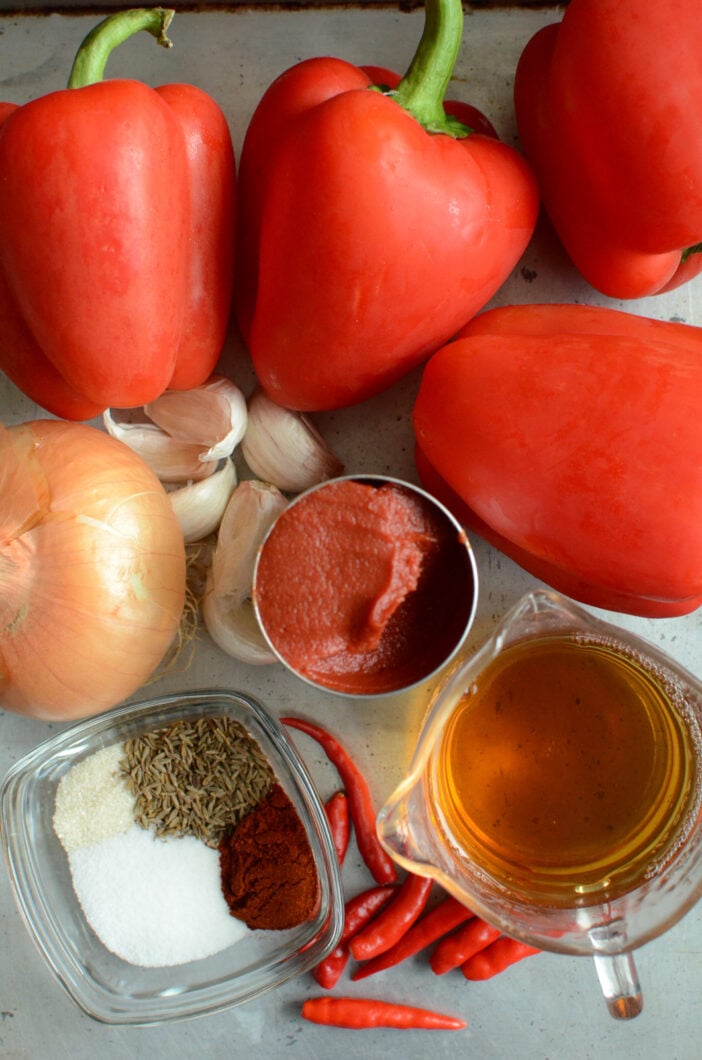 Harissa ingredients. Red peppers, apple cider vinegar, bird's eye chilies, spices, onion, garlic, and tomato paste. 